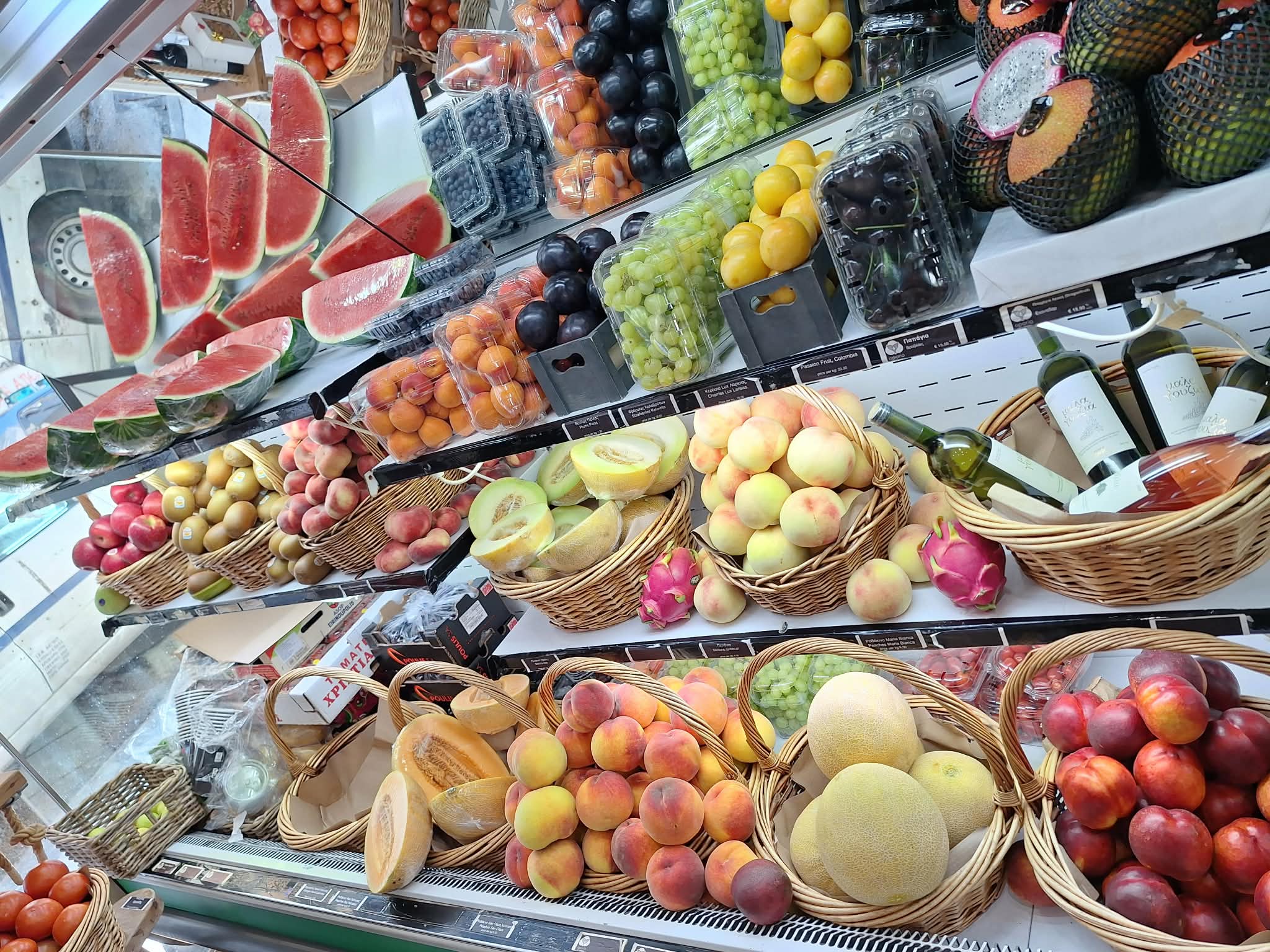 Πλούσια βιτρίνα με καρπούζι, σταφύλια, ροδάκινα και πεπόνια στο Οπώριο